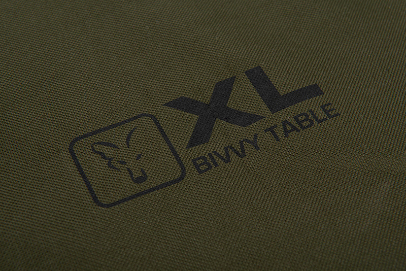 Лого на Маса FOX XL Bivvy Table с тъмен фон, идеално за риболовни приключения.