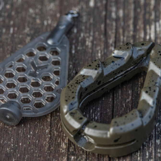 Олово KORUM Bait Gripper Leads, showing fishing accessories on a wooden surface.