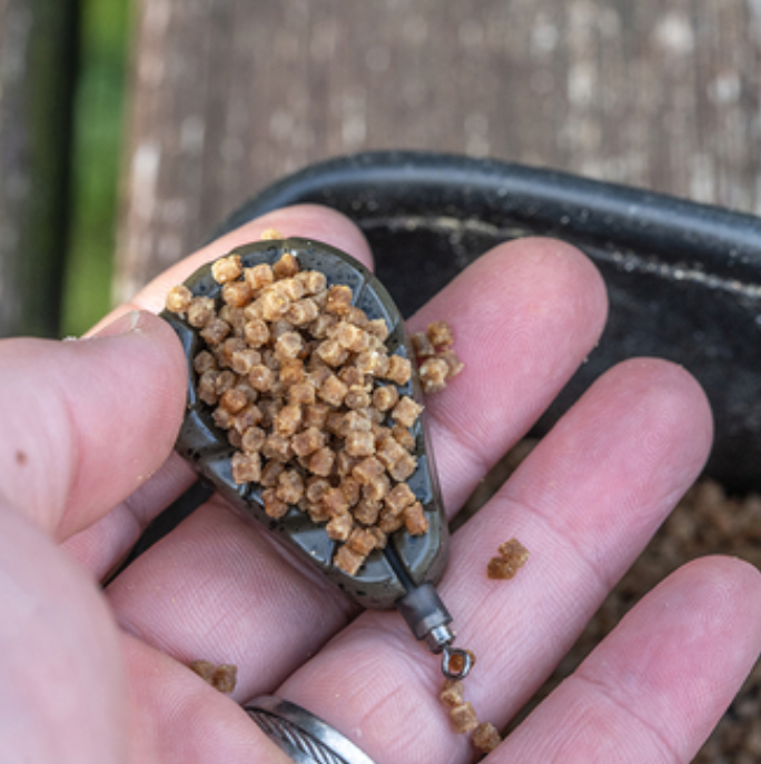 Олово KORUM Bait Gripper Leads with bait in hand, showcasing fishing accessories for effective angling.