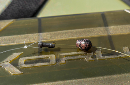 Бързи връзки KORUM Camo Quick Change Bead - S/L shown on a fishing surface, featuring a black and pink bead.