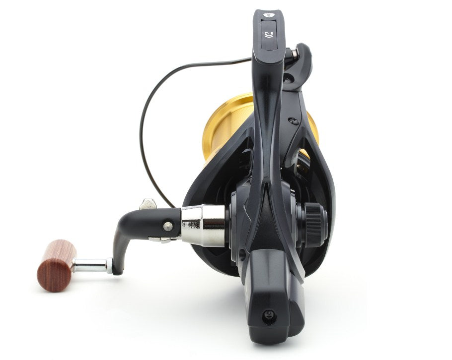 Шаранджийска макара DAIWA 23 EMBLEM 45 SCW QD-OT с черен и златен дизайн и дървена ръкохватка.