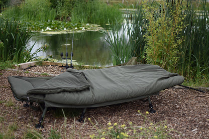 Легло DAIWA IFS Sleep System на брега на вода, идеално за комфортен сън по време на риболов.