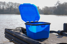 Кутия за стръв и захранка PRESTON 3 PINT FLIP LID BAIT TUB на риболовен плот близо до вода.
