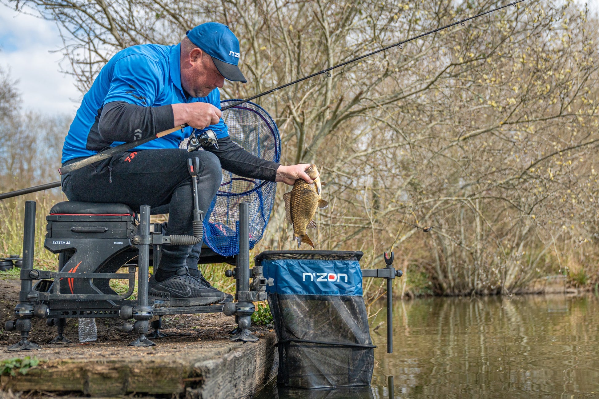 Рибар, който държи риба с преден държач за въдица DAIWA N'ZON COMPACT FRONT ROD REST на водоема.