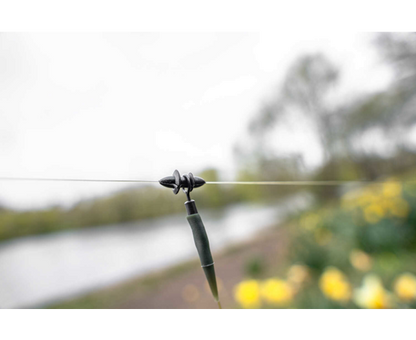 Готов монтаж KORUM SPECI HELI KIT на рибарска линия с аксесоар и цветя на фона.