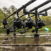 Регулируема стойка за 2 въдици AVID Lok Down Adjustable Buzz Bar с рибарски макара на водния фон.