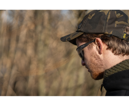Поляризирани слънчеви очила AVID CARP SeeThru OptiWrap Grey Lens на мъж с камуфлажна шапка на открито.