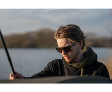 Мъж с поляризирани слънчеви очила AVID CARP SeeThru AV Classic Polarised Sunglasses, риболов на фона на езеро.