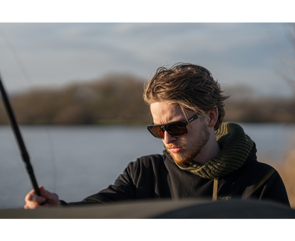 Мъж с поляризирани слънчеви очила AVID CARP SeeThru AV Classic Polarised Sunglasses, риболов на фона на езеро.