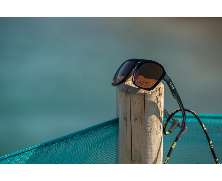 Поляризирани слънчеви очила AVID CARP SeeThru AV Classic Polarised Sunglasses поставени на дървено стълбче