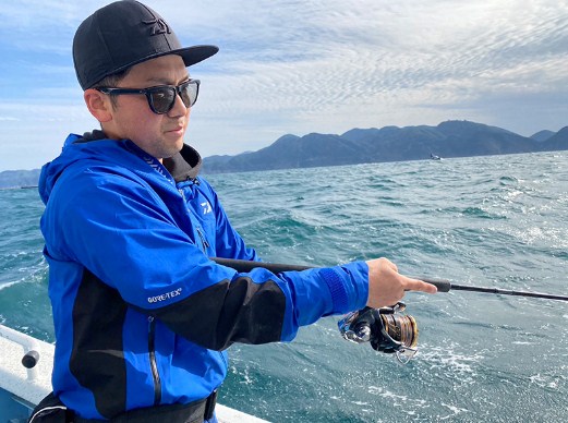 Риболовец с Макара Daiwa 22 CALDIA SW (JP) на лодка, хвърлящ въдица в морето.