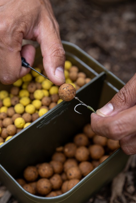 Кутия KORUM DIVIDED BAIT TUB с разделена стръв и рибарски куки, идеална за риболовни сесии.