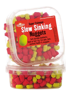 Дъмбели Dynamite Baits Super Fishmeal Slow Sinking Nuggets в опаковка с червени и жълти стръвни топчета.