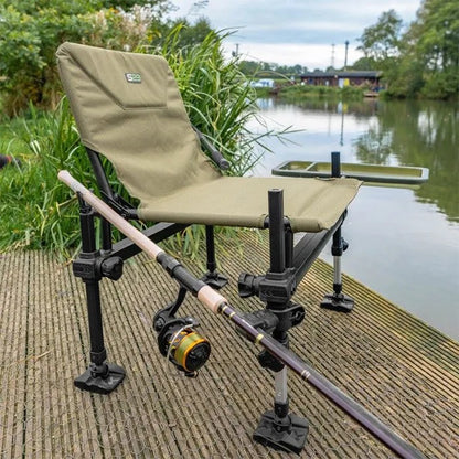 Сгъваем стол KORUM S23 - ACCESSORY CHAIR COMPACT, поставен до водоем с риболовна пръчка.