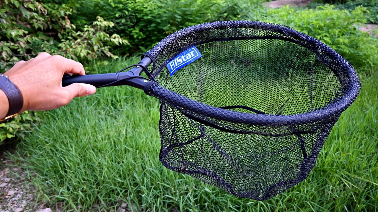 Кеп FILSTAR Pro Float Net - Oval 50×40см held in hand against lush green background.