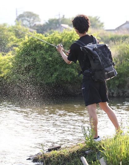 Водоустойчива чанта за спининг риболов JACKALL WATERPROOF BACKPACK L (30L - 35L) - Черна, риболовец в действие.