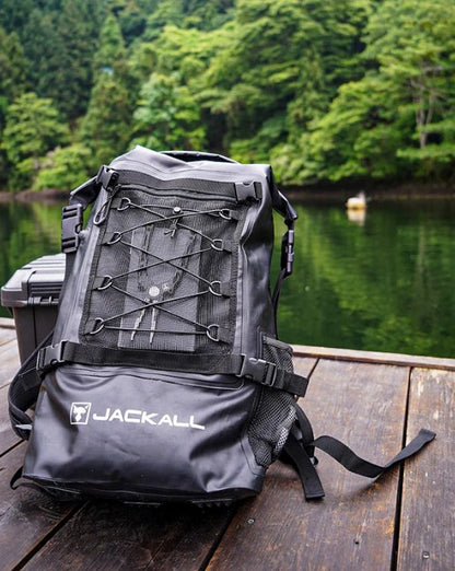 Водоустойчива чанта за спининг риболов JACKALL WATERPROOF BACKPACK L (30L - 35L) - Черна на фона на водоем.