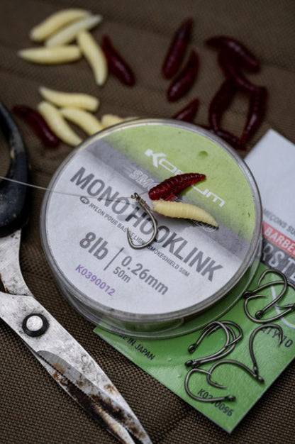 Изкуствени плуващи бели червеи Korum FLOATING GRUBS - IMITATION MAGGOTS и риболовни аксесоари на работна повърхност.