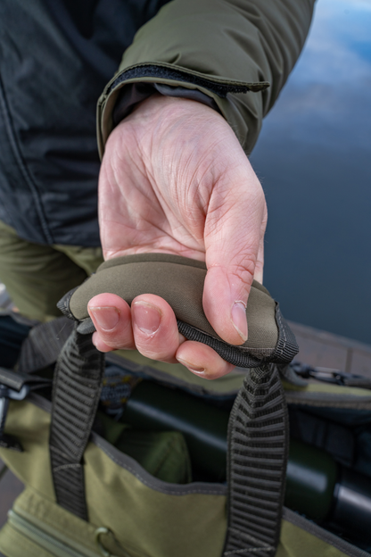 Чанта KORUM Progress Bait & Bits Bag - 25L with comfortable grip handle in hand by the water.