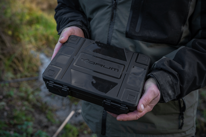 Кутия с инструменти KORUM Slim Blox Loaded held by a person outdoors, perfect for organizing fishing gear.
