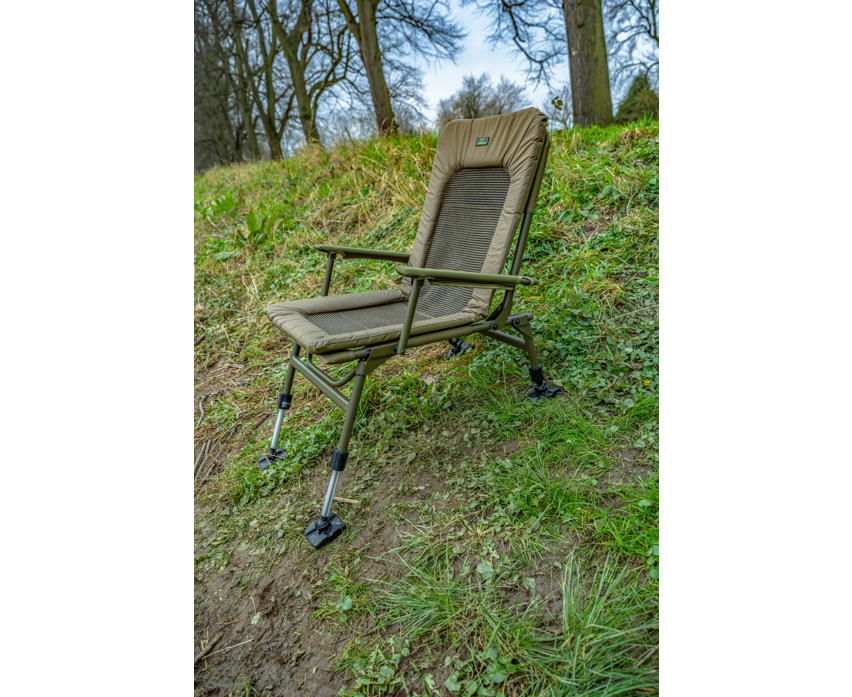Луксозен фидер стол KORUM Supa Lite Stretch - Deluxe Chair на тревата, с удобна облегалка и издръжлива конструкция.