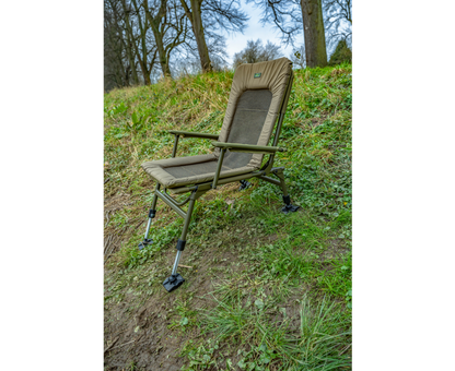 Луксозен фидер стол KORUM Supa Lite Stretch - Deluxe Chair на тревата, с удобна облегалка и издръжлива конструкция.
