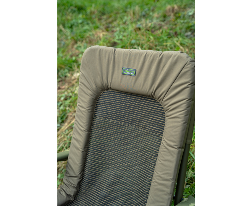Луксозен фидер стол KORUM Supa Lite Stretch - Deluxe Chair с удобна и устойчива облегалка на тревиста поляна.
