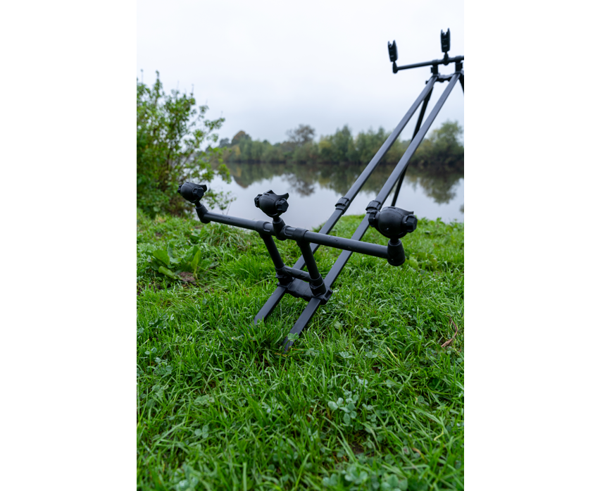 Родпод Korum DELUXE 3 ROD TRIPOD в зелена тревна площ до водоем, осигуряващ стабилност за 3 въдици.