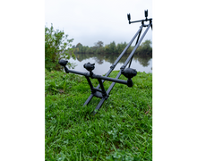 Родпод Korum DELUXE 3 ROD TRIPOD в зелена тревна площ до водоем, осигуряващ стабилност за 3 въдици.