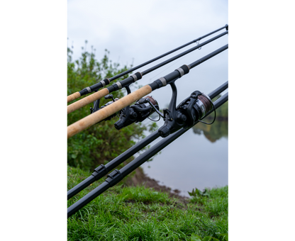 Родпод Korum DELUXE 3 ROD TRIPOD с три въдици и ролки на фон на река.