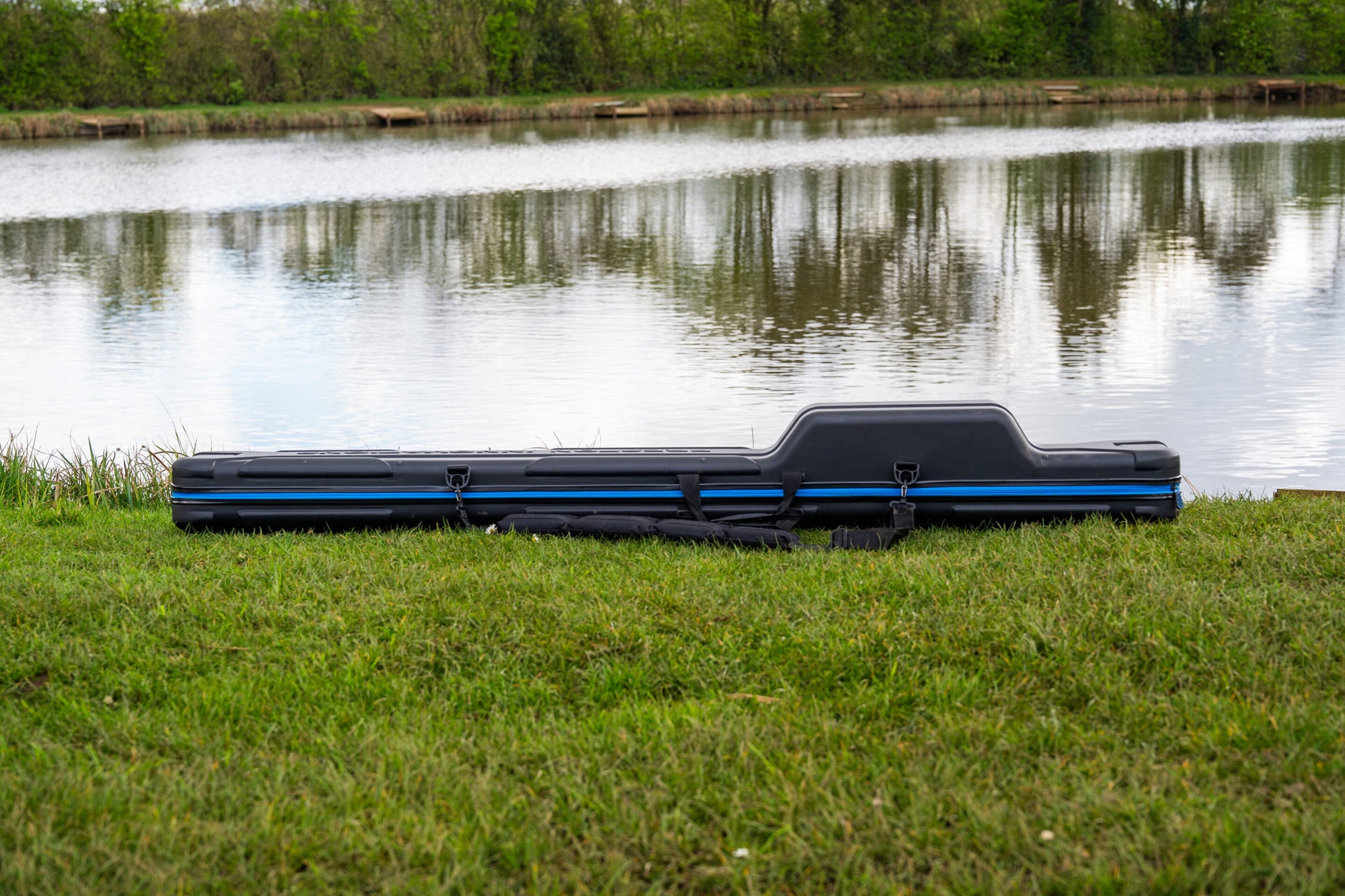 Твърд калъф PRESTON HARDCASE ROD SAFE на трева до водоем, предназначен за съхранение на въдици.