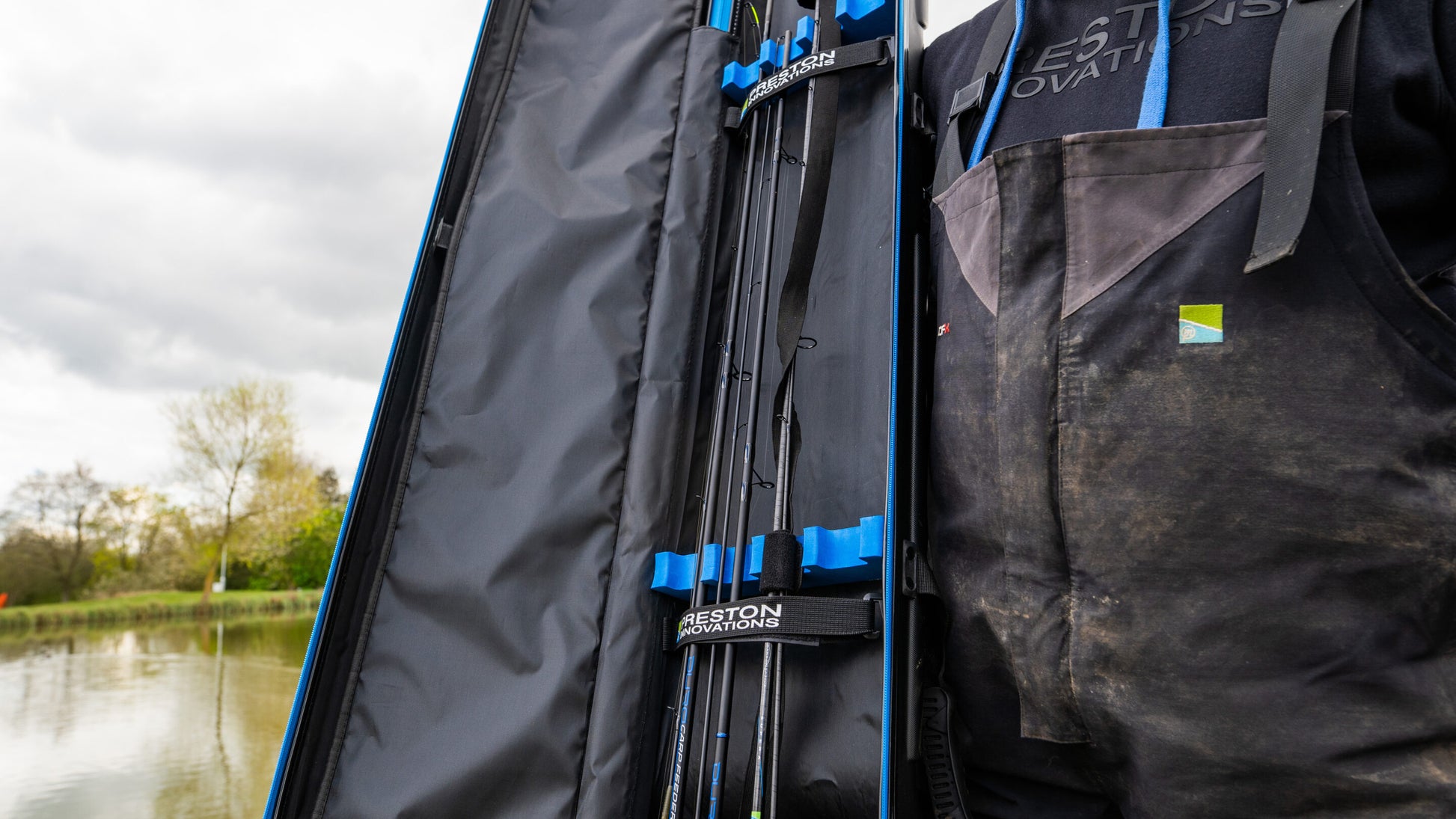 Твърд калъф PRESTON HARDCASE ROD SAFE, показващ риболовни пръчки в организиран калъф на водоем.