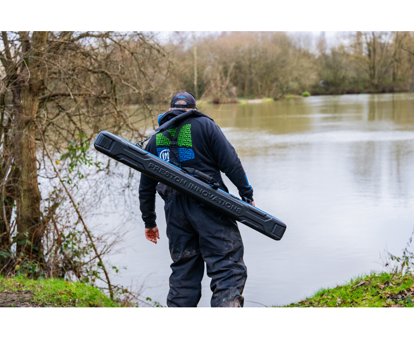 Твърд калъф PRESTON HARDCASE COMPACT KIT SAFE carried by an angler near a river.