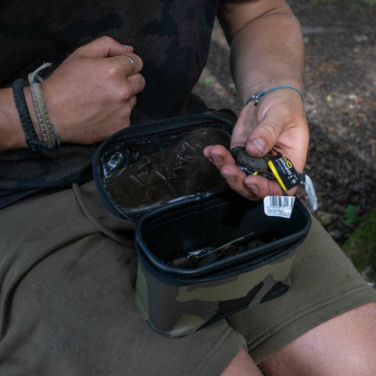 Чанта AVID STORMSHIELD PRO POUCH being used outdoors with a hand holding fishing tackle.