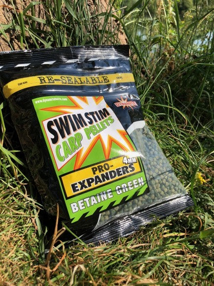 Пелети Dynamite Baits Pro Expanders - Betaine Green in natural setting with grass and tree backdrop.