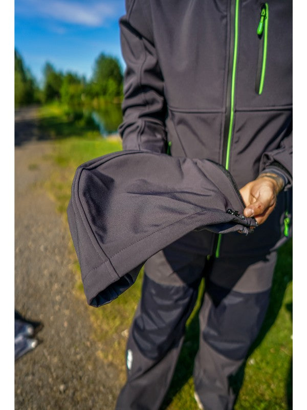 Мъж в яке MAVER PERFORMANCE SOFTSHELL JACKET държи ръкав от якето, показвайки детайли и качество на материала.