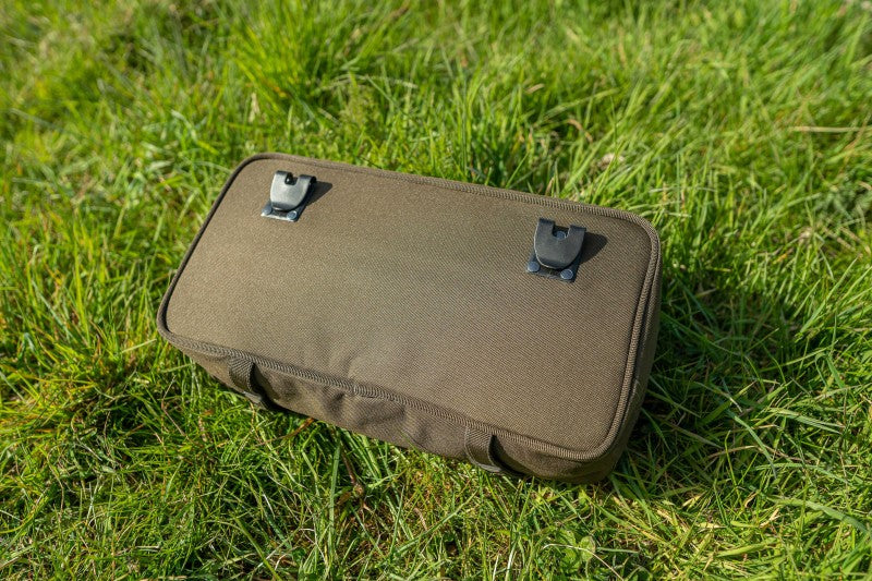 Чанта AVID Compound Pouch върху зелена трева с клик-система за прикрепване на аксесоари.