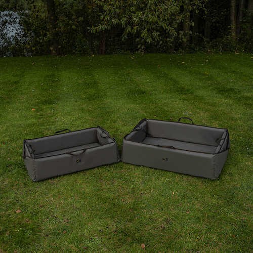 Карп люлка AVID Folda Cradle - Standard/XL on grass by the water, showcasing two sizes.