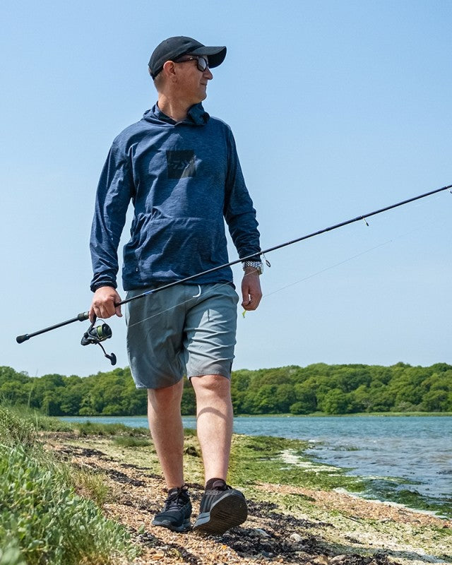 Мъж в тъмен суичър DAIWA LIMITED EDITION SUN PROTECT HOODIE, риболов в природата.
