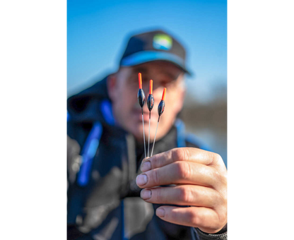 Плувки - PRESTON - EDGE XS POLE FLOAT, представени в ръката на риболовец на фона на синьо небе.